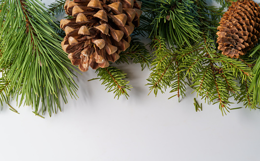 A Christmas composition. A frame of pine and fir branches and fir cones and Christmas balls and decorations on a white background. Flat layout, top view, copy space.