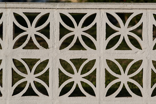 Intricate, stone blocks with curly design built into a property border fence.