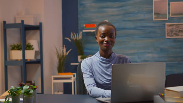 istock African-american woman looking at camera smiling working at pc 1869507452