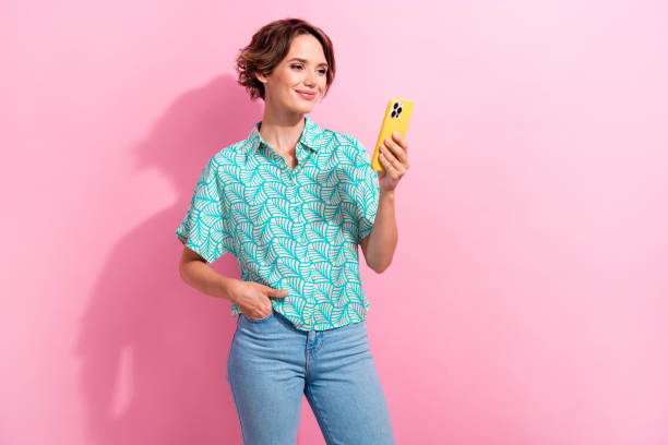 istock Portrait of gorgeous lady use smart phone texting write post empty space ad isolated on pink color background 1869509608