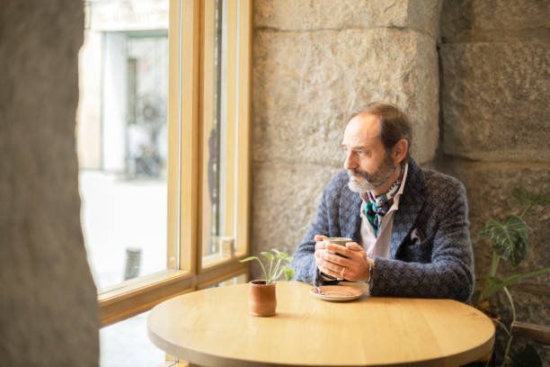 Senior man with beard in a cafe with hot cup in hands
