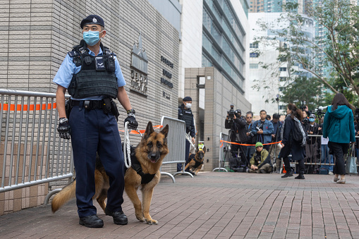 Dec 18,2023,Hong Kong.A police officer with a police dog outside the West Kowloon Magistrates' Courts ahead of a hearing for former media mogul Jimmy Lai in Hong Kong.