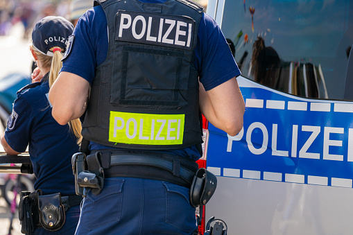 Germany, Berlin, September 16, 2023 -Rear view of police officers in front of police car, Berlin Tempelhof