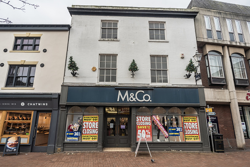 Nantwich, Cheshire, England, January 22nd 2023. M And Co shop window with sale and store closing display, retail and business editorial illustration.