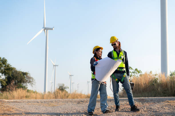 istock Engineer and worker discussing on a wind turbine farm with blueprints 1869538159