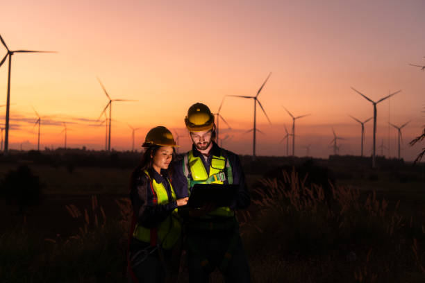 istock Engineers working on wind turbines farm at sunset, Wind turbines are alternative energy source. 1869539738