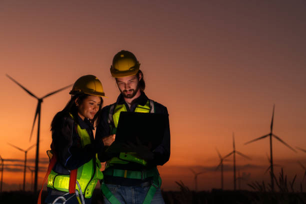 istock Engineers working on wind turbines farm at sunset, Wind turbines are alternative energy source. 1869539746