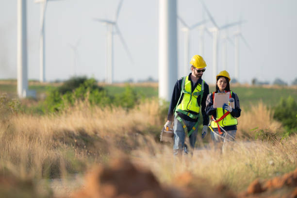 istock Engineer and worker discussing on a wind turbine farm with blueprints 1869540797