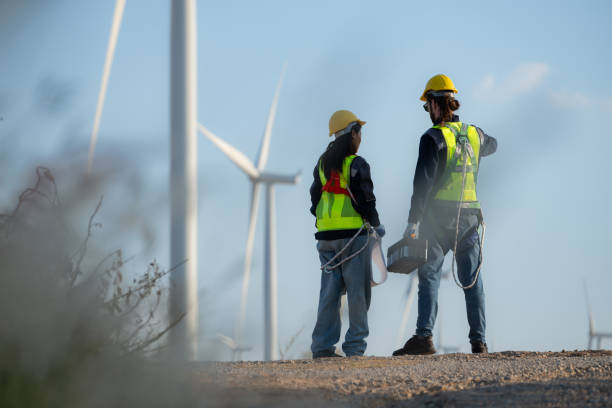 istock Engineer and worker discussing on a wind turbine farm with blueprints 1869540818