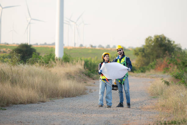 istock Engineer and worker discussing on a wind turbine farm with blueprints 1869541359