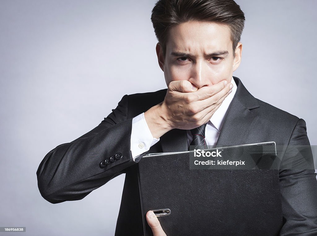 Young business man covering his mouth Young business man covering his mouth  trying to keep a secret. (copy space) Business Person Stock Photo
