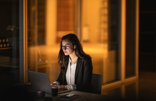 Businesswoman working and using computer in dark office