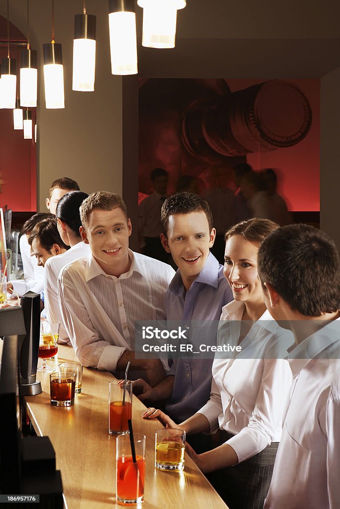 Coworkers at bar Group of young women and men at bar, talking during informal meeting after work 18-19 Years Stock Photo