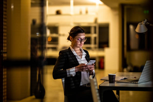 istock Businesswoman using computer in dark office 1869571813