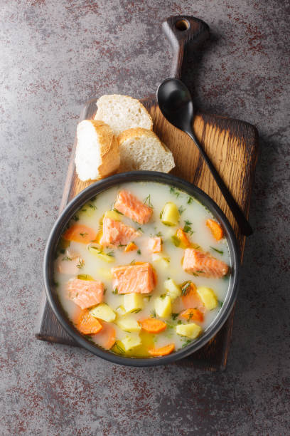 istock Creamy red fish soup with vegetables on a plate served with bread close-up. Vertical top view 1869572375
