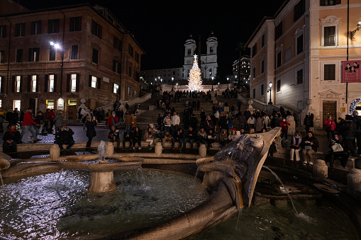 Rome, Italy - December 19, 2023: Christmas decorations and light in Piazza di Spagna, with people shopping, in a cold winter afternoon blue hour on December 19, 2023 in Rome, Italy. People shopping complete the composition.