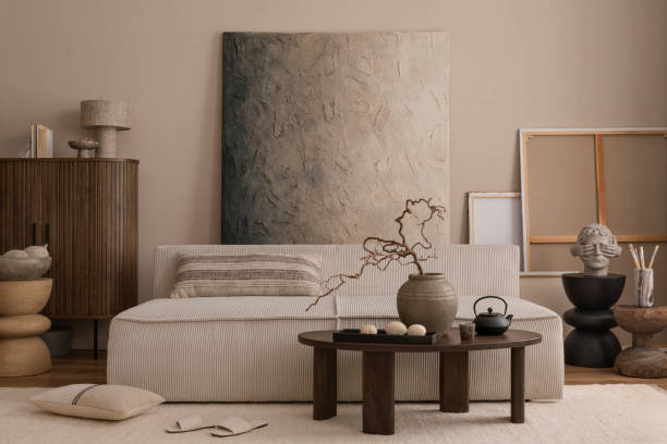 istock Creative composition of cozy living room interior with mock up poster frame, modular sofa, wooden coffee table, vase with branch, beige carpet, wooden sideboard, black stand, pillow. 1869598570