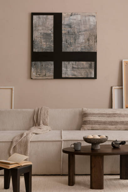 istock Creative composition of living room interior with mock up poster frame, modular sofa, wooden coffee table, beige pillow, plaid, carpet, marble bowl and personal accessories. Home decor. Template. 1869598599