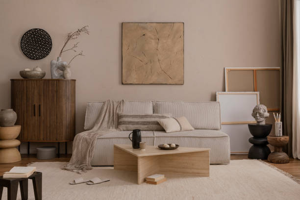 istock Warm and cozy living room interior with mock up poster frame, modular sofa, pillows, sideboard, marble coffee table, plaid, slippers, pillows and personal accessories. Home decor. Template. 1869598604