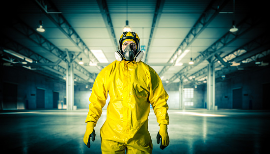 man in mask and protective clothing inside an empty warehouse