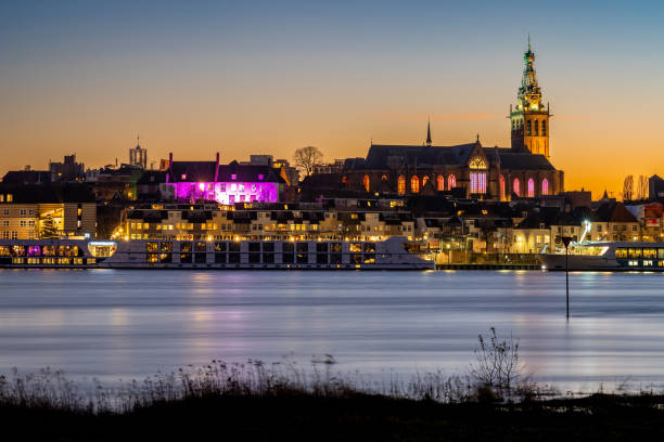 Dutch city of Nijmegen in the evening, Waterfront of river Waal and majestic Steven's Church Steven's Church in Nijmegen with river Waal in the foreground in the evening clear sky night sunset riverbank stock pictures, royalty-free photos & images