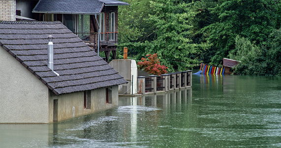 Slovenia - August 04, 2023; Flooded water flowing through river surrounded by houses in village.\n\nFlooding is an overflowing of water onto land that is normally dry. Floods can happen during heavy rains. Heavy floods destroy many parts of Slovenia in the begining of August 2023.