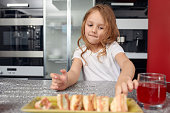Cute smiling little girl with sushi on white background. Child girl eating sushi and rolls - commercial concept.
