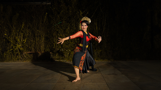 a Balinese dancer wearing a red dress with artistic details that add uniqueness to her appearance at night