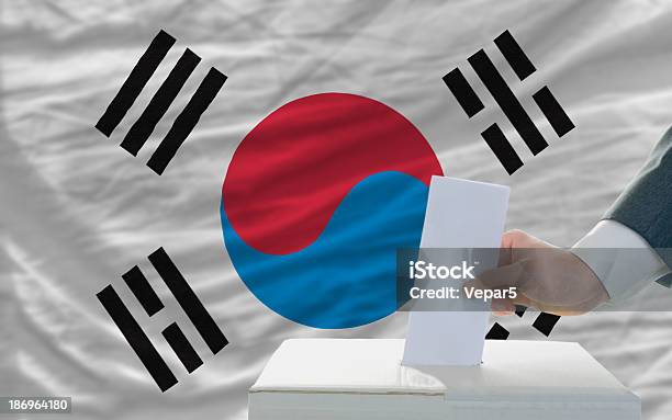 Hombre De Voto En Las Elecciones En Frente De Bandera De Corea Del Sur Foto de stock y más banco de imágenes de Adulto