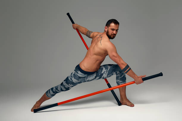 istock A ninja man holds on to a fighting stick and attacks close-up on gray studio background 1869643484