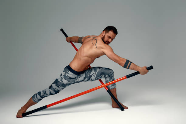 istock A ninja man holds on to a fighting stick and attacks close-up on gray studio background 1869644041