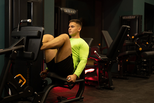 Young man exercising on leg press exercise machine in gym.