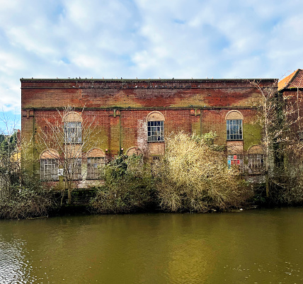 Overgrown derelict building on the banks of the River Wensum in Norwich, Norfolk. December 2023