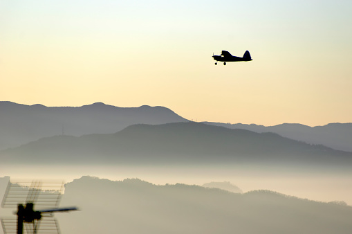 airplane silouette above a panorama of hills and fog