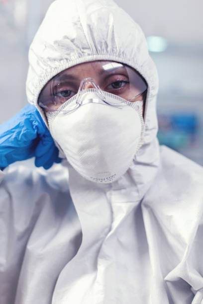 istock Tired laboratory doctor with overall suit looking at camera in equipped lab 1869679809