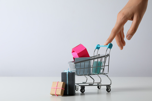 Shopping cart with gift boxes, miniature, with hand.