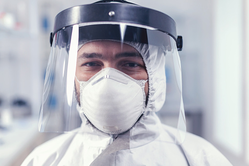 Portrait of biochemist in science laboratory wearing ppe equipment for covid19. Overworked researcher dressed in protective suit against invection with coronavirus during global epidemic.