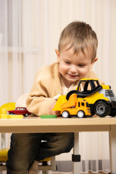 istock Little cute boy playing with toys while sitting at table 1869704667