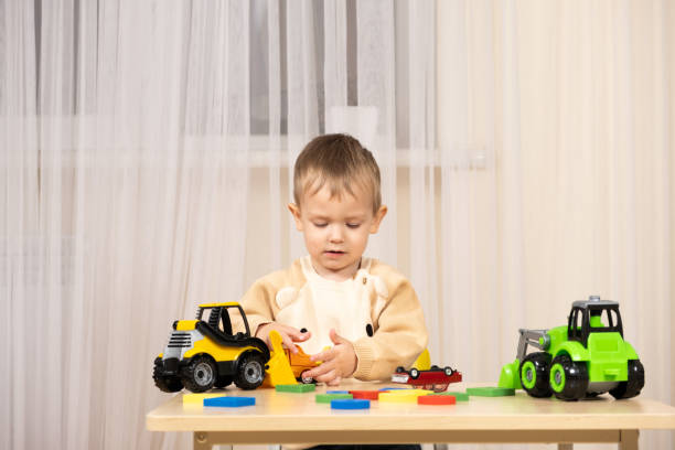 istock Little cute boy playing with toys while sitting at table 1869704674