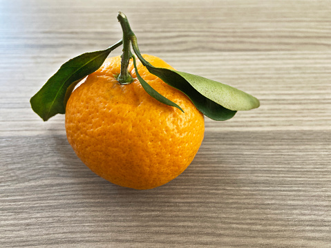 Fresh organic tangerine with leaf on wood background with copy space