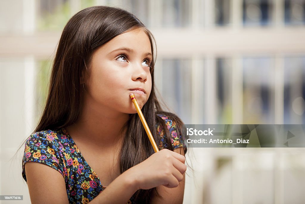Solving a problem for homework Gorgeous little girl looking up toward copy space and thinking while holding a pencil near her mouth Beautiful People Stock Photo