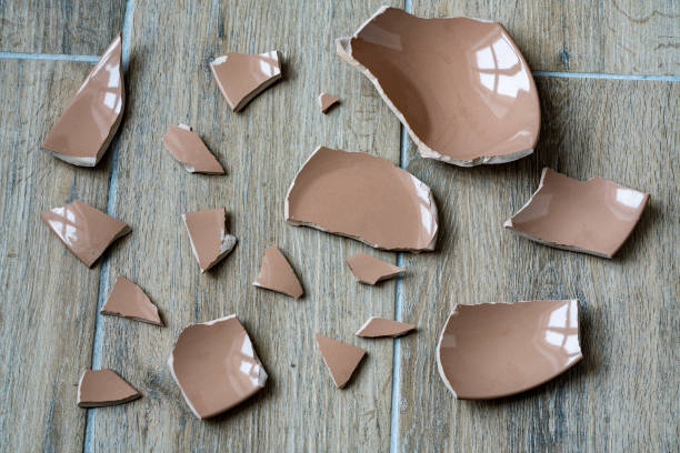 istock Broken ceramic beige plate on floor in kitchen, closeup. Shards and pieces of a broken dish 1869716867