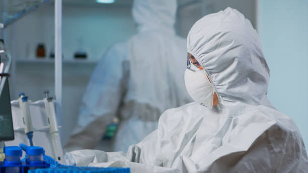 istock Close up of scientist in protection suit typing on pc 1869718469