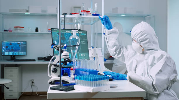 istock Biochemists in coverall typing at pc evolution of vaccine composition 1869726490
