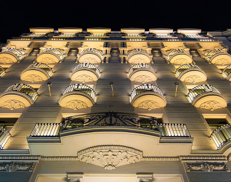 Beautiful night wiew of illuminated historical building facade with old style balconies in Barcelona, Spain.