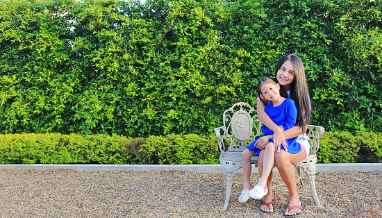 Mother and daughter sitting together on luxury Europe style chair in the garden.