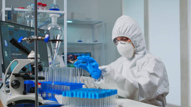 istock Lab technician in coverall examining samples of liquid 1869740639