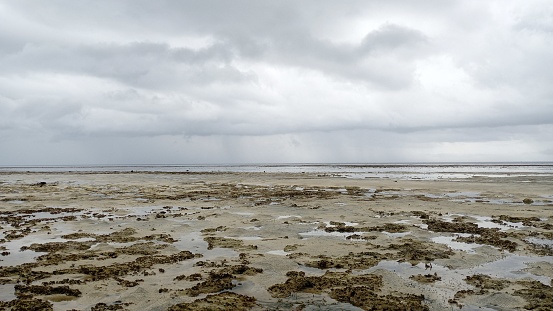 Sea water recedes in the morning on a coastal beach with a slightly cloudy sky b