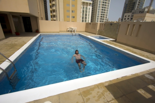 man swim in swimming pool at roof of apartment, bahrain