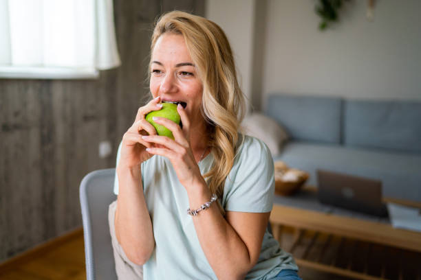 istock Happy woman eating an apple at home 1869760257